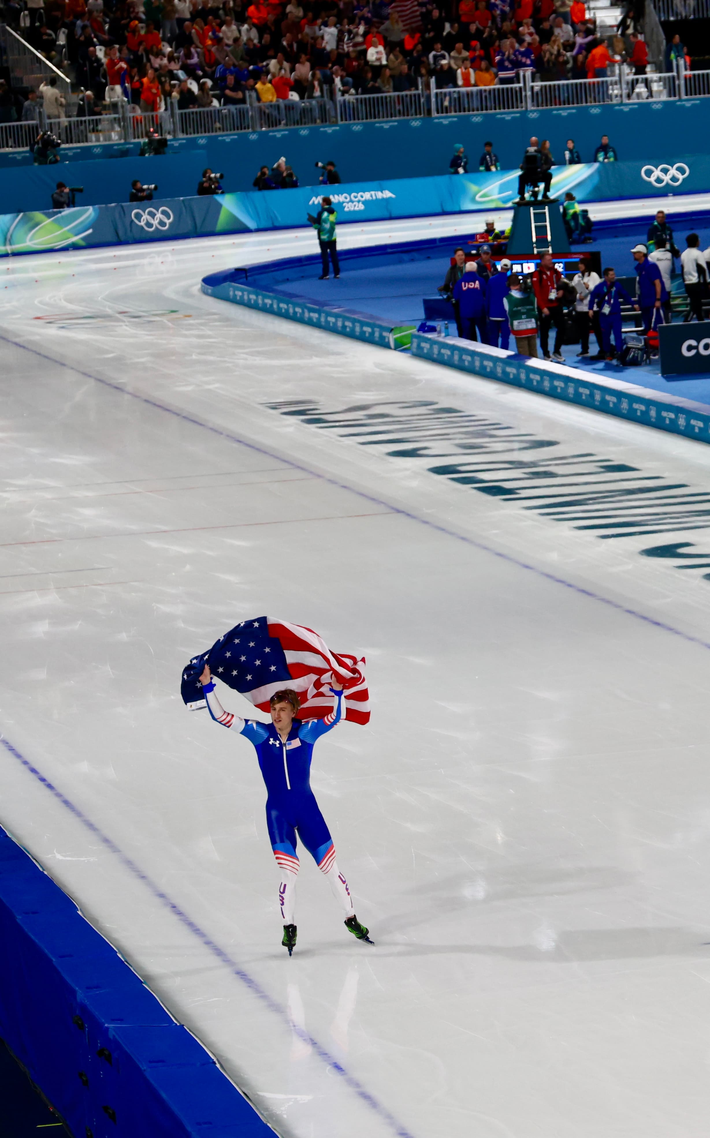 USA speed skater carrying the American flag on a victory lap at Milano Cortina 2026