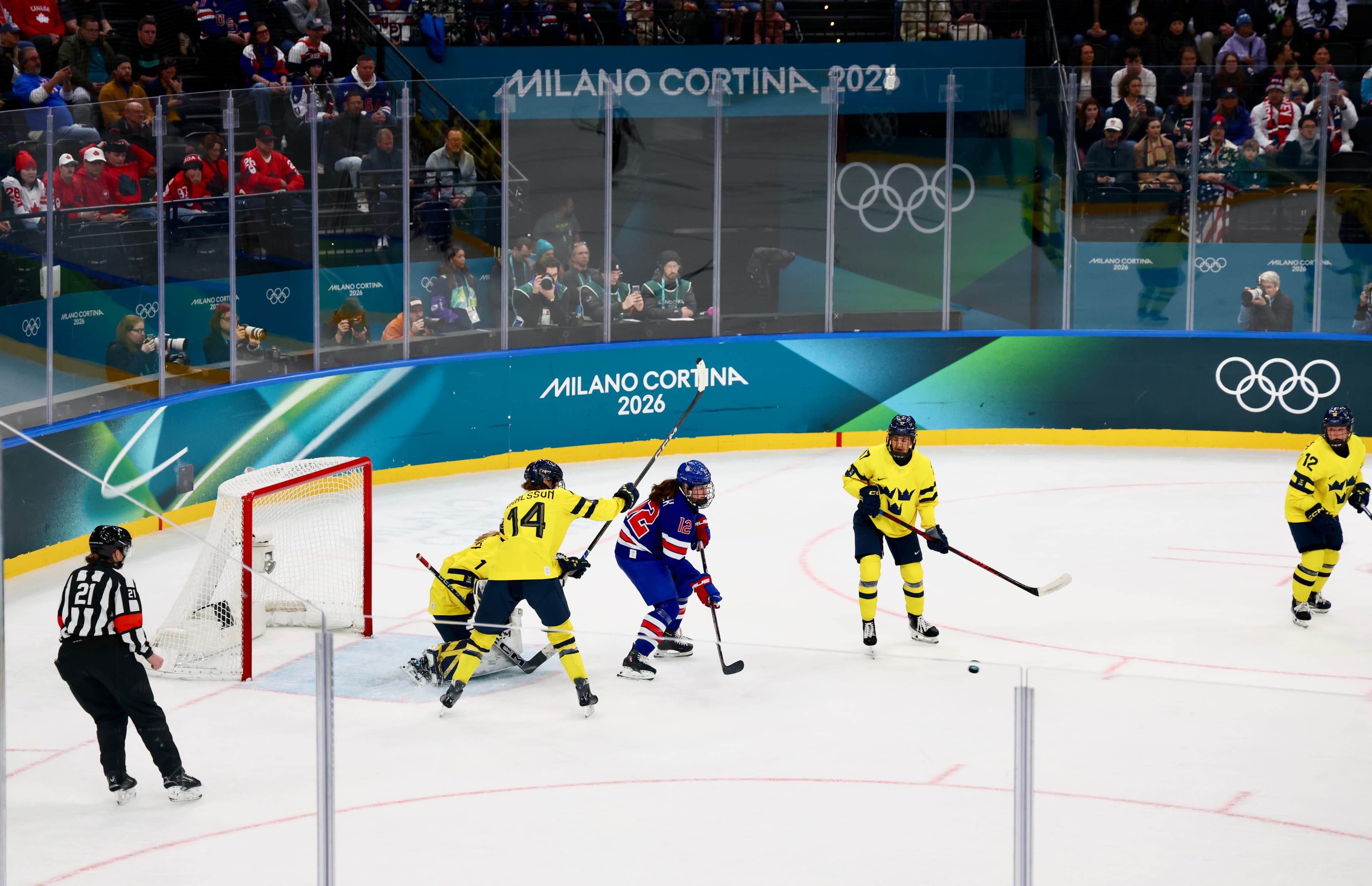 USA and Sweden players battling in front of the net at Milano Cortina 2026, Olympic rings on boards